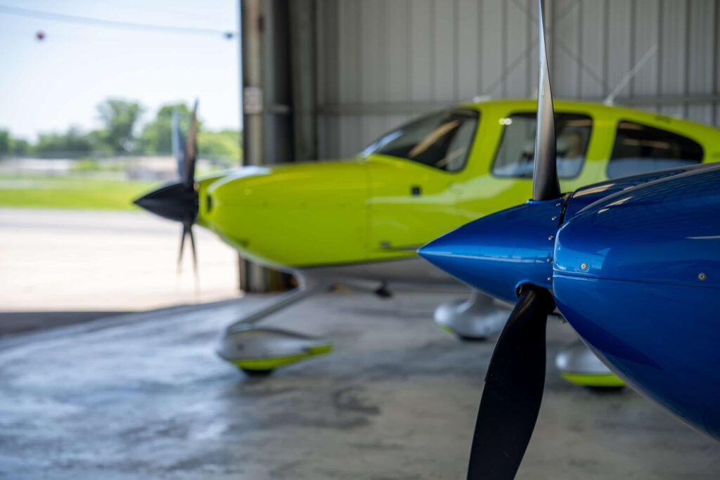 A Cirrus and a Cessna parked together in the hangar at Bowman Field